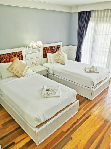 two beds in a hotel room with white furniture at โรงแรม ริเวอร์บรีซ เชียงแสน River Breeze Chiangsean in Chiang Saen