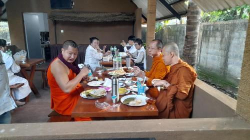 a group of monks sitting at a table eating food at Hotel Sanhida Polonnaruwa in Polonnaruwa