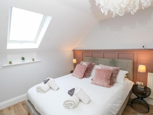 une chambre avec un grand lit blanc avec des oreillers roses dans l'établissement Cambrie, à Tenby