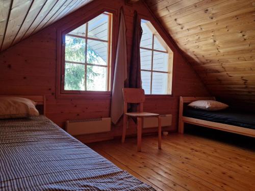 a bedroom with two beds and a chair in a attic at Villa Korpikallio in Naantali