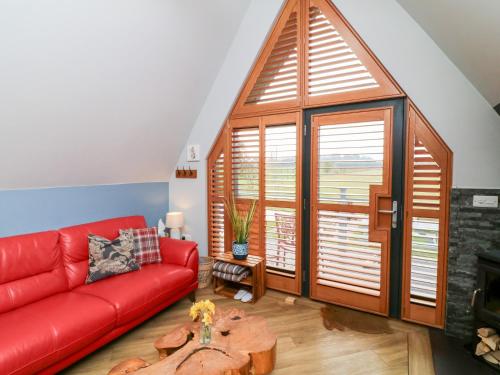 a red couch in a living room with a large window at Silver Birch Lodge in Bawtry