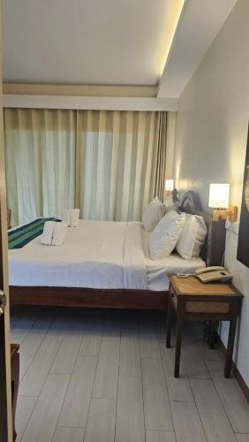 a bedroom with a large bed and a table at Chada Mantra Hotel in Chiang Mai