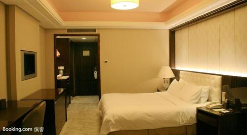 a hotel room with a bed and a desk with a phone at Shu Guang International Hotel in Nanjing