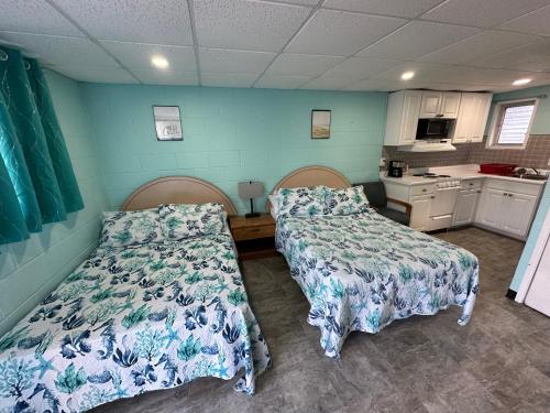 two beds in a room with blue walls and a kitchen at Old Orchard Beach Motel in Old Orchard Beach