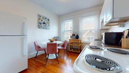 a kitchen with a table and a white refrigerator at Sunny,spacious, Sleeps 4, Steps To Mbta,hospitals in Brookline