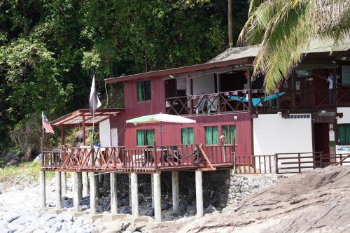 a red house with a deck on the beach at Tioman Beruntun Hideaway in Tioman Island