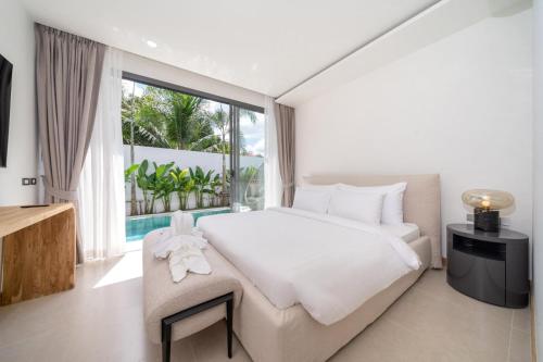 Ban Phru ChampaにあるCoco Villas Phuket - 3 Bedroom Deluxe Garden Pool Villa by Escape Villasの大きな白いベッドと大きな窓のある寝室