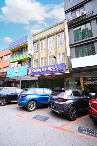 eine Gruppe von Autos, die auf einem Parkplatz vor den Gebäuden geparkt werden in der Unterkunft Swing & Pillows - Subang SS15 in Subang Jaya