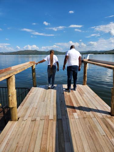 a man and a woman walking on a dock at Le Bamboo Guest House And Boat Cruise in Hartbeespoort