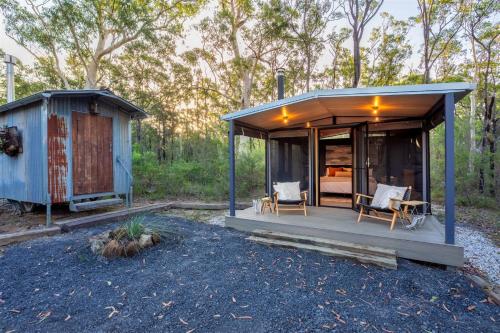 a small shed with two chairs and a bed at The Hollows - Kangaroo Valley in Kangaroo Valley