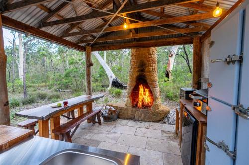 an outdoor kitchen with a fireplace in a house at The Hollows - Kangaroo Valley in Kangaroo Valley