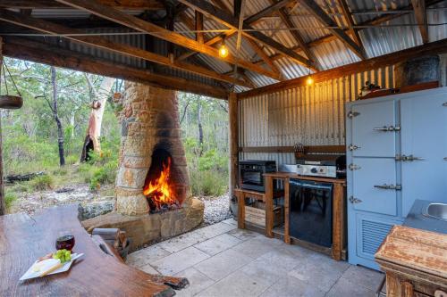 an outdoor kitchen with a stone fireplace in a house at The Hollows - Kangaroo Valley in Kangaroo Valley