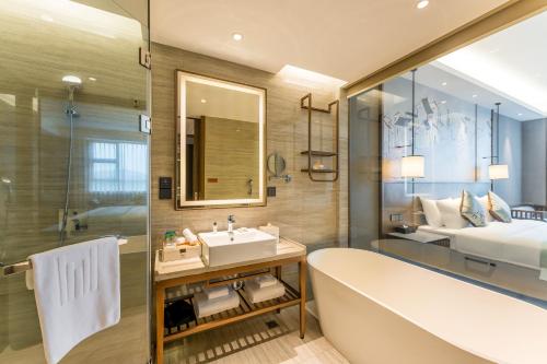 a bathroom with a tub and a sink and a bed at Millennium Resort Wuyishan in Wuyishan