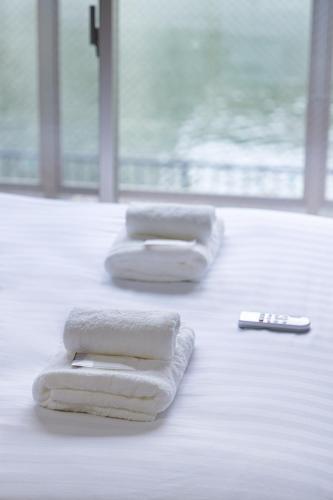 two towels on the floor with a remote control at R Home Sakuragawa Riverside in Osaka