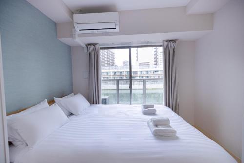 a bedroom with a bed with two towels on it at R Home Sakuragawa Riverside in Osaka