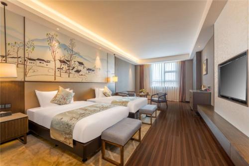 a hotel room with two beds and a flat screen tv at Millennium Resort Wuyishan in Wuyishan