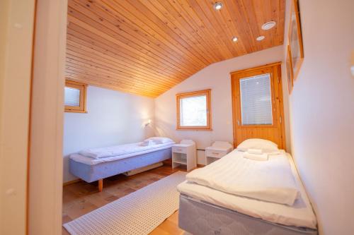a bedroom with two beds and a wooden ceiling at Vaeltajanmaja in Saariselka