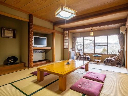 a living room with a wooden table and a living room with a tv at Shirayunoyado Yamadaya Hakone Gora in Hakone