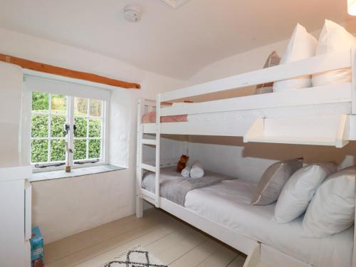 a bedroom with bunk beds and a window at 2 Rose Cottage in St. Agnes 