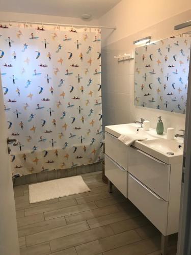 La salle de bains est pourvue d'un lavabo et d'un rideau de douche avec des papillons. dans l'établissement Mimizan Plage 4 bedroom house with garden, à Mimizan-Plage