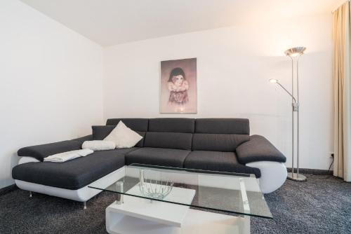 a living room with a black couch and a glass table at Airporthotel Residenz Steinenbronn in Steinenbronn