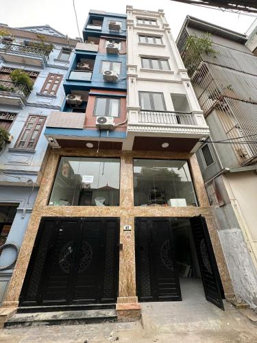 a tall white building with black doors and windows at The Little Hanoi - Cool Apartment - Lakeside in Hanoi