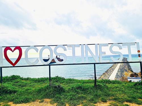 a sign with the word costliest in front of the ocean at I love Costinesti in Costinesti