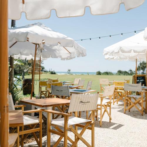 a group of tables and chairs with white umbrellas at BreakFree Aanuka Beach Resort in Coffs Harbour
