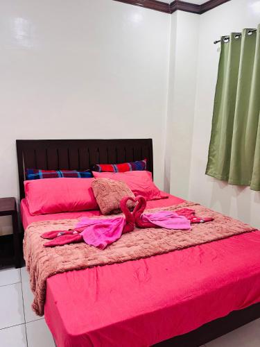 a bed with pink sheets and pillows on it at M and M Apartment in Surigao