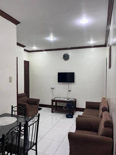 a living room with couches and a tv on a wall at M and M Apartment in Surigao