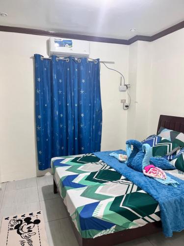 a bedroom with a bed and a blue curtain at M and M Apartment in Surigao