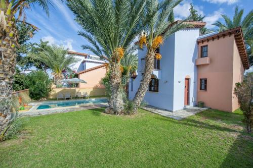 a villa with a swimming pool and palm trees at The Olympians Villas in Polis Chrysochous