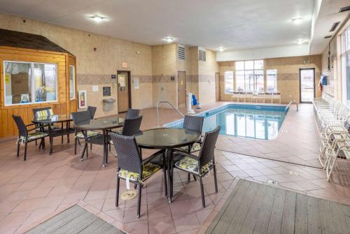 a pool room with tables and chairs and a swimming pool at Super 8 by Wyndham Big Rapids in Big Rapids