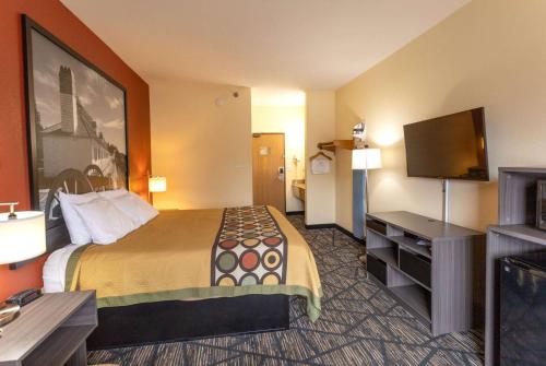 a hotel room with a bed and a flat screen tv at Super 8 by Wyndham Big Rapids in Big Rapids