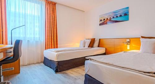 a hotel room with two beds and a desk at Best Western Macrander Hotel Frankfurt/Kaiserlei in Offenbach