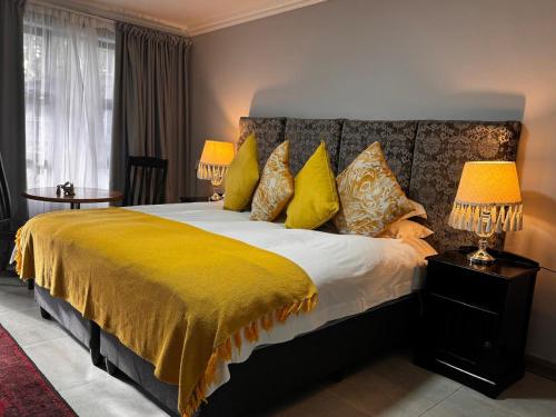 a bedroom with a large bed with yellow sheets and lamps at Rabbit Hole Hotel in Krugersdorp