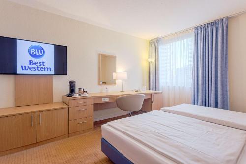 a hotel room with a bed and a desk and a television at Best Western Macrander Hotel Frankfurt/Kaiserlei in Offenbach