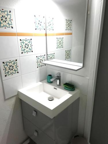 une salle de bain blanche avec un lavabo et un miroir dans l'établissement Bel appartement à 100 m de la plage, à Carcans