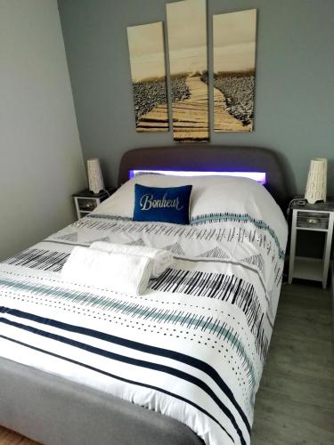 - un lit dans une chambre avec 3 photos sur le mur dans l'établissement Bel appartement à 100 m de la plage, à Carcans