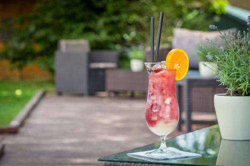 a drink sitting on a table with an orange slice at Best Western Macrander Hotel Frankfurt/Kaiserlei in Offenbach
