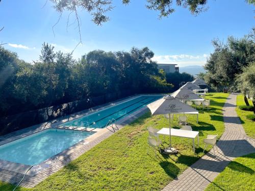 una piscina con sombrillas y sillas junto a un complejo en Modern Retreat & Workspace In Dainfern, en Midrand