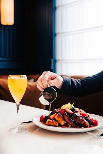 a person holding a glass of wine next to a plate of food at Conrad Nashville in Nashville