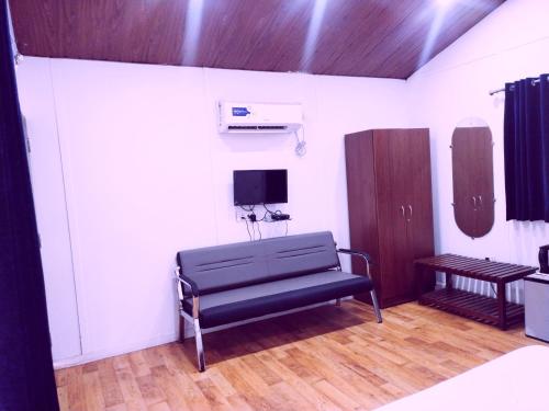 uma sala com um banco e uma tv em uma sala em Samant Beach Resort em Malvan