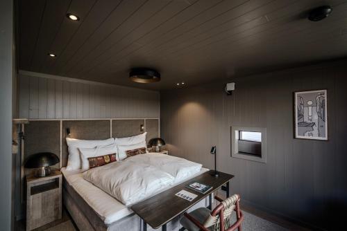 a bedroom with a large bed and a table at Henningsvær Bryggehotell - by Classic Norway Hotels in Henningsvær