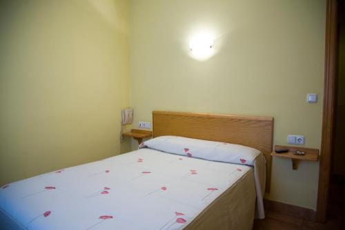 a small bedroom with a bed with pink flowers on it at Hostal Orejas in León