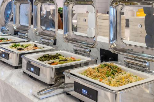 a buffet with four trays of food on a counter at XANA Hotel Qionghai Municipal Government High-speed Railway Station in Qionghai