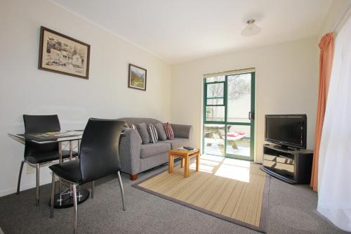 a living room with a couch and a table and a television at Blue Marlin Apartments in Whitianga