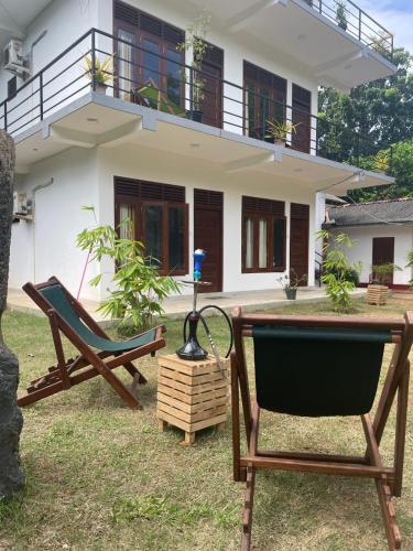 two chairs and a table in front of a house at Saimon Villa in Mirissa