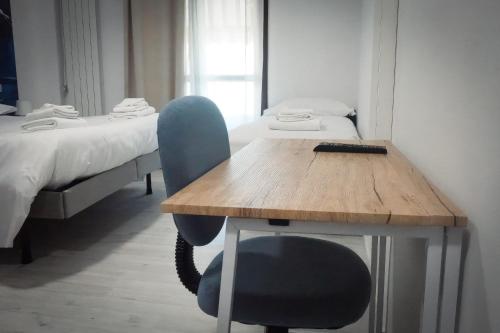 a table and a chair in a room with two beds at La Boheme SMART Hotel in Turin