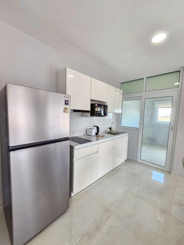 a kitchen with a stainless steel refrigerator and white cabinets at View Talay6 by Blue Ocean Suite in Pattaya Central